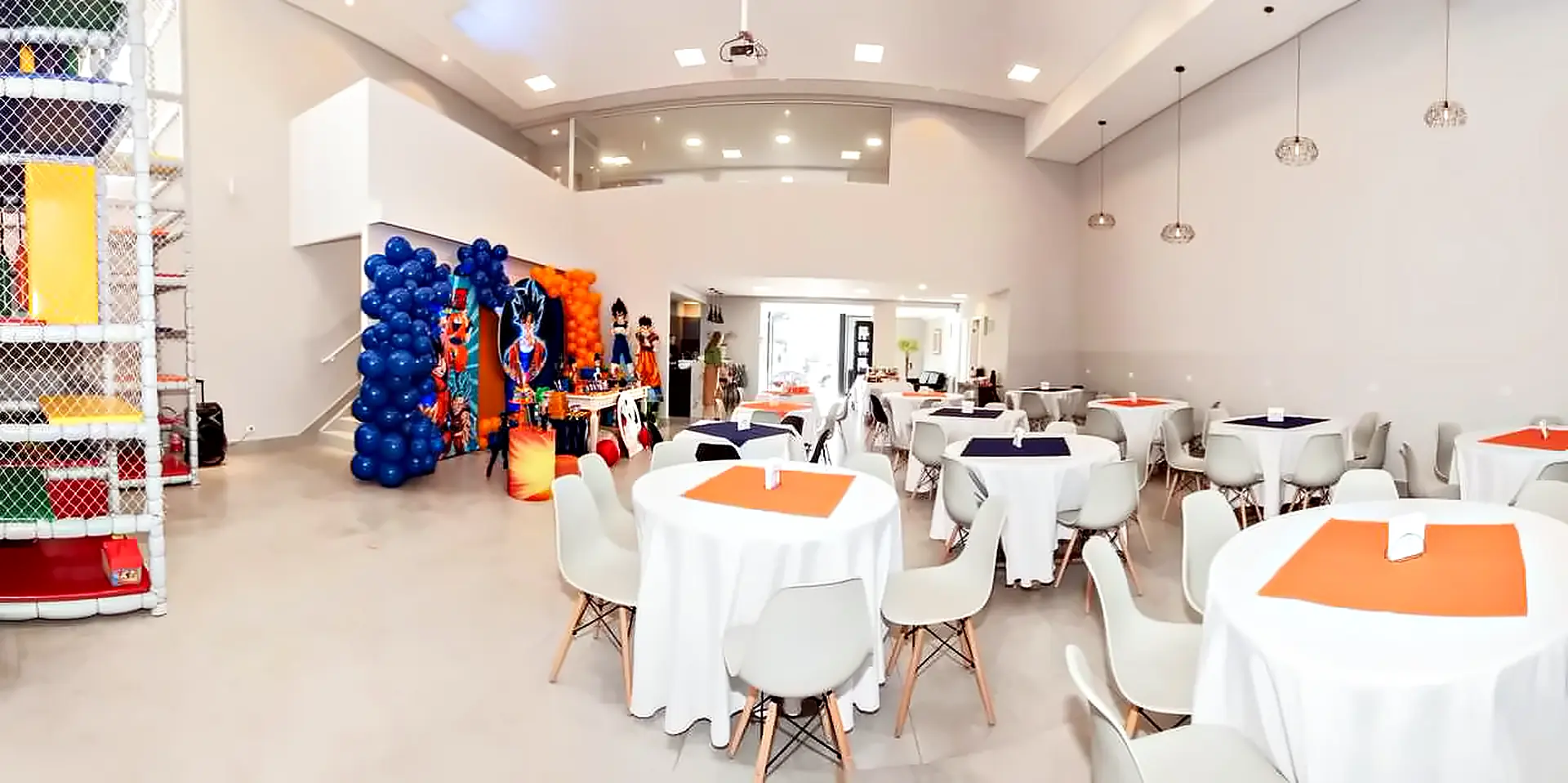 Vista ampla do salão montado, com mesas redondas, mezanino envidraçado e mesa principal decorada